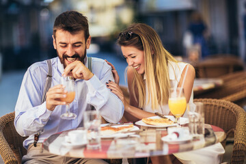 Attractive and happy young couple having good time in cafe restaurant. They are smiling and eating a pizza.