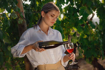 Vintner woman tasting red wine from a glass in a vineyard - 436815289