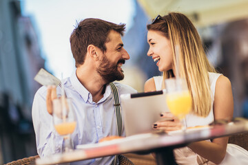 Young couple buying online with credit card and tablet in a coffee shop.