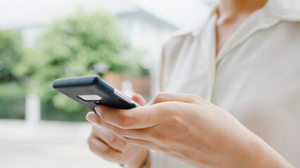 Attractive young Asia businesswoman using mobile phone checking social media internet, chatting...