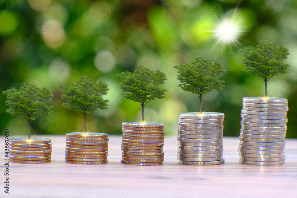 Sticker Saving money concept and stacking coins on table on green bokeh background, business growth concept, finance and investment concept, Advertising coins of finance and banking 