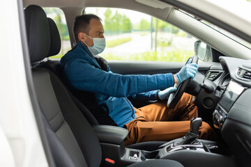 Covid-19 concept. Man drives in car, wears medical gloves, protects himself from bacteria and virus, holds car steering wheel. Coronavirus protection. Transport, quarantine and corona disease.