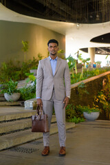 Full length shot of African businessman holding bag and looking at camera