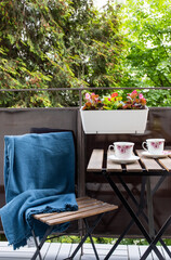 bright small apartment terrace in summer with flowers and coffee table