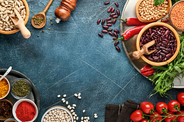 Legumes, lentils, chickpea, beans assortment, tasty appetizing ingredients spices grocery for cooking healthy kitchen on black table. Weight loss diet and fight against cholesterol concept. Top view.