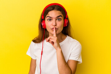Young caucasian woman listening to music isolated on yellow background keeping a secret or asking...
