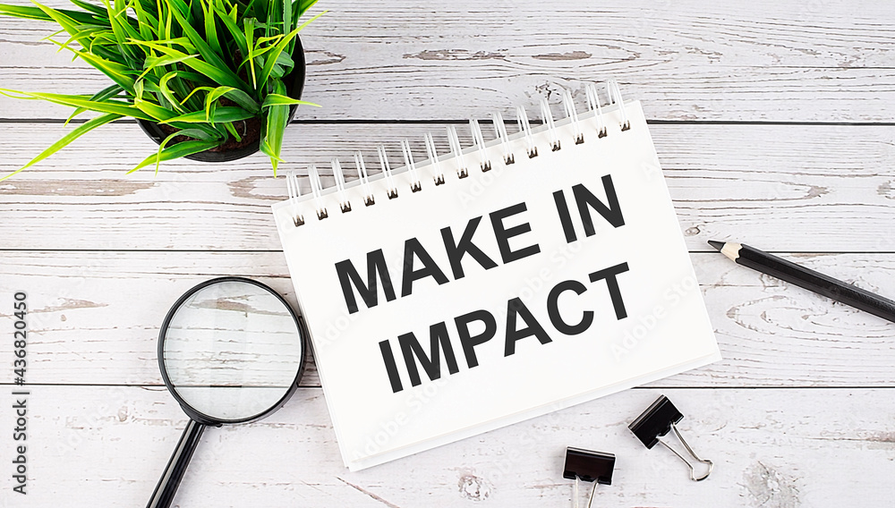 Aufkleber make in impact text concept write on notebook with office tools on wooden background