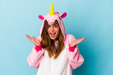 Young caucasian woman wearing a unicorn pajama isolated on blue background surprised and shocked.