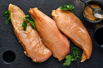 Raw chicken meat fillet marinated in teriyaki soy sauce, onions, garlic and pepper in black plate on a dark slate, stone or concrete background. Top view with copy space. © kasia2003