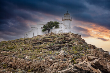 Kea island, Greece. Lighthouse Tamelos on a rocky cliff, cloudy sky background