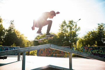 Skater is doing ollie on the ramp in a skatepark in sunny day