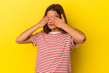 Young caucasian woman isolated on yellow background afraid covering eyes with hands.