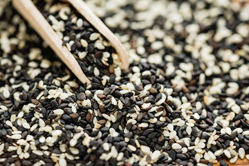 Close up of mix of black and white sesame seed on wooden spoon background