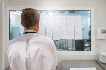 Fototapeta premium Chef looking at his work list. Scenes in motion of real teamwork by great Spanish professionals of gourmet haute cuisine for social events. 