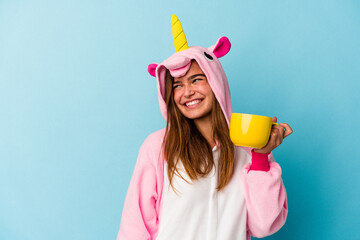 Young caucasian woman wearing an unicorn costume holding a mug isolated © Asier