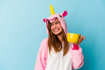 Young caucasian woman wearing an unicorn costume holding a mug isolated