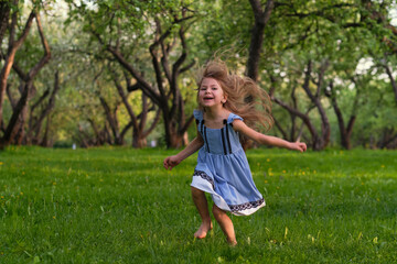 Obraz premium little girl runs barefoot on the grass. happy child on a hot summer day.
