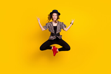 Fototapeta na wymiar Full body photo of crazy young woman jump up stick out tongue make rock sings isolated on yellow color background