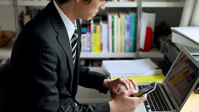 自宅の書斎で仕事をするスーツの男性