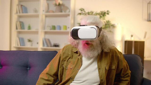 Senior man wearing virtual reality googles, playing video game, stunned by image