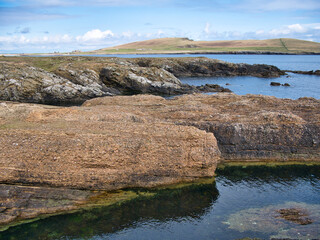 Conglomerate rock (fore) and inclined strata (behind) on the Ness of Burgi, south Shetland, UK -...