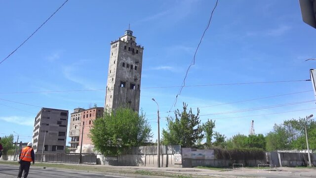 An industrial building explodes in controlled demolition on a sunny day.Slow motion