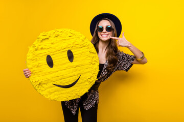 Photo of cheerful positive happy lady point finger smile hold hand emoji paper pinata isolated on...