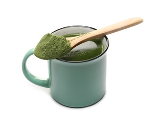 Organic green wheat grass herbal liquid, medicinal drink in mug with powder in wooden spoon isolated on white background