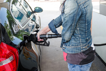 Obraz premium Woman's hand with gloves holding hose from gas pump