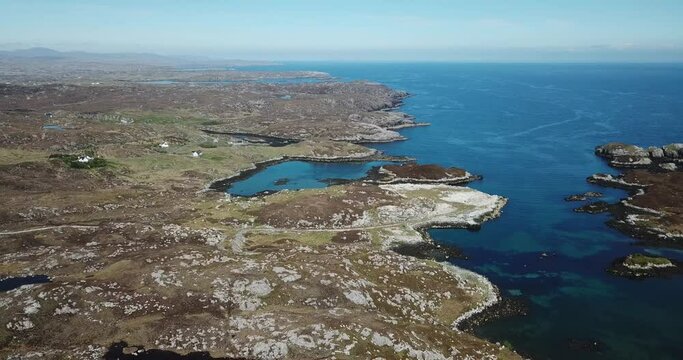 4k aerial footage of the rocky east coast of Isle of Harris on a sunny day with blue sky on horizon. Showing rocky landscape, blue sea, snaking single track road.