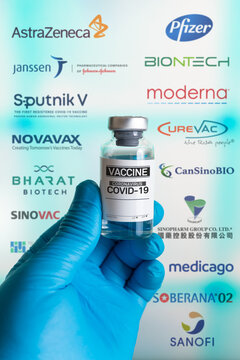 Madrid, Spain, June 1, 2021. Bottle Generic Vaccine And In The Background The Screen With Logos Companies That Develop The Vaccine Covid-19 With Clinical Trials And Investigations In Phase 2, 3 And 4