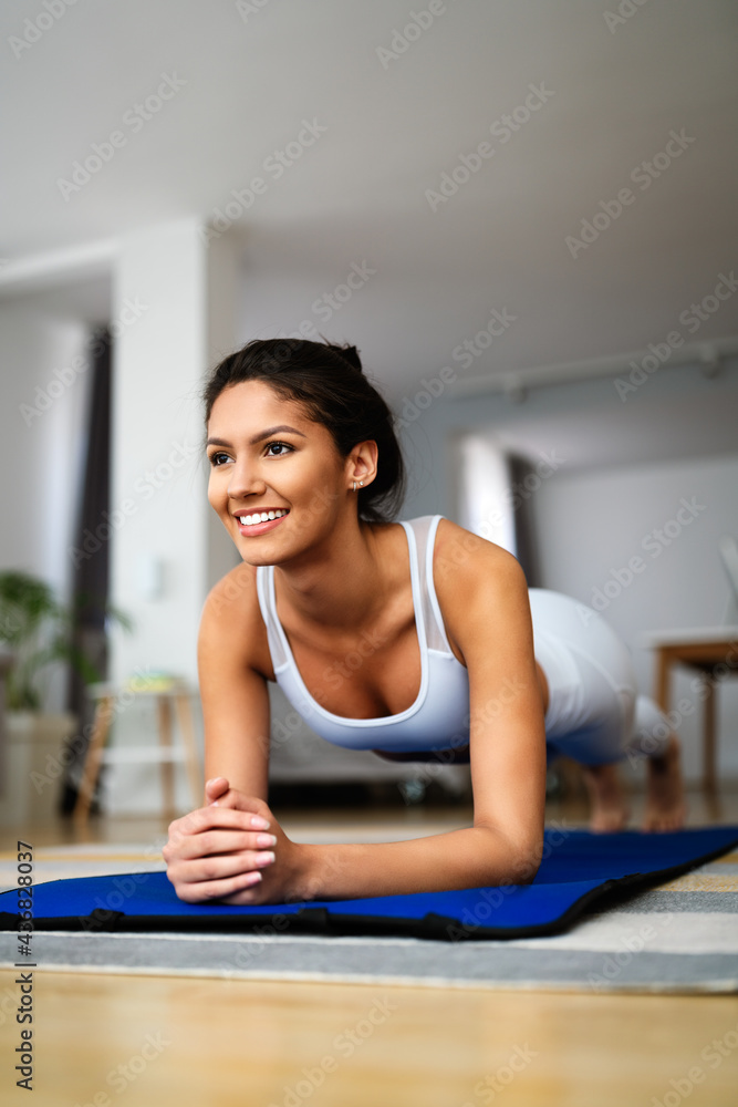 Wall mural Stay at home. Fitness at home during quarantine. Young attractive woman in sportswear training