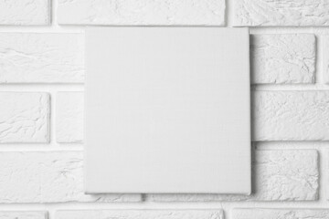 Blank canvas hanging on white brick wall, space for text