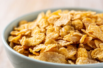 Corn flakes in a blue bowl on wooden table. Close up