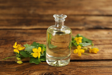 Obraz na płótnie Canvas Bottle of natural celandine oil near flowers on wooden table, closeup