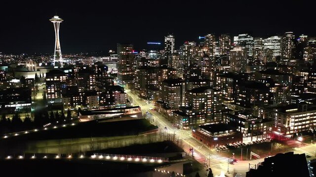 Cinematic 4K drone, night clip of the Space Needle downtown Seattle, Washington, Alaskan way waterfront with illuminated streets and offices looking from Elliott Bay Seattle Harbor during blue hour