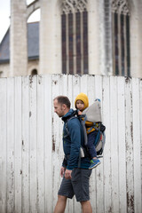 Happy family, father and sons, walking in village in France, visiting famous places, dad carrying toddler in a carrier backpack