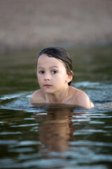 Children, playing in a lake on sunset, swimming and running, splashing water, summertime