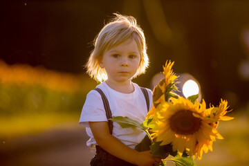 Little toddler boy, child in sunflower field, playing with big flower