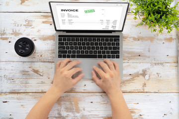 Close-up of businessman's hands working on invoice on laptop at office