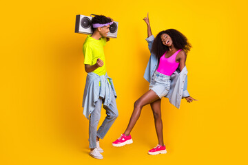 Photo of charming sweet young people wear jeans clothes dancing holding boombox isolated yellow color background
