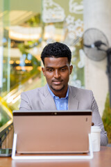 African businessman at coffee shop using laptop computer vertical shot