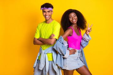 Portrait of attractive cheerful couple showing v-sign good mood isolated over bright yellow color...