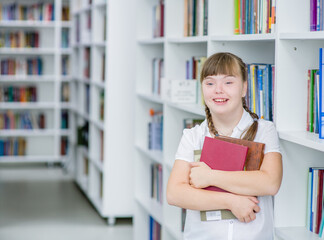 Portrait of a smiling girl with syndrome down at library. Empty space for text. Education for disabled children concept