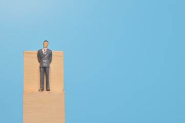 Businessman miniature standing on wooden block with copy space. Leadership concept