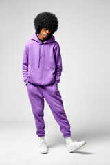 Young black man in set of purple tracksuit isolated on gray background