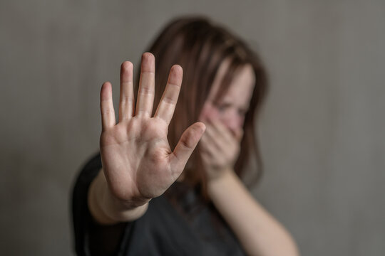 Crying teenage girl showing a stop sign with her hand. Focused on the hand