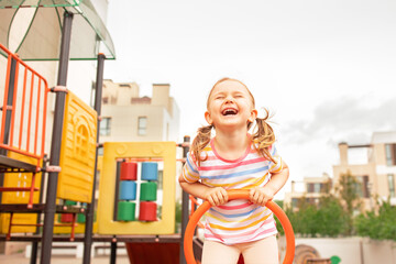 Funny child girl playing on playground outdoor.Laughing expression kid playing seesaw with mother.Happy moment and good emotion.Active sport leisure for children.Copy space, place for text