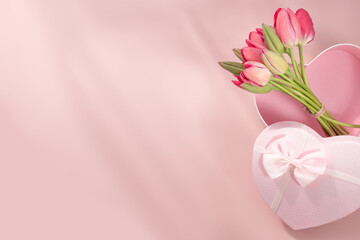 Bouquet of pink tulips and gift box on pink background. Copy space. Horizontal orientation.