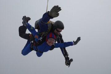 Fototapeta na wymiar Skydiving. Tandem jump. A young woman and her instructor are in the sky. 